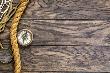 Vintage compass, magnifying glass and hawser rope on old wooden table with copy space