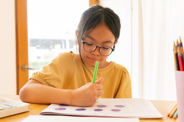 Naklejka na ściany i meble Young girl asian sitting and painting watercolour artwork to develop abilities and improve mental health at home. Female artist drawing with inspiration.