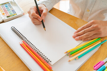 Man asian sitting and painting watercolour artwork to develop abilities and improve mental health at home. Female artist drawing with inspiration.