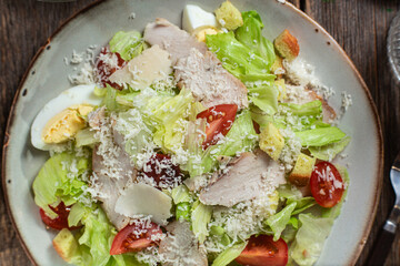 Appetizing Caesar salad in a plate on a wooden table