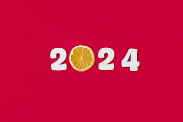Happy New year 2024 number wood object on red background with a slice of orange instead of the number zero and copy space - red color new year celebrate and business resource concept