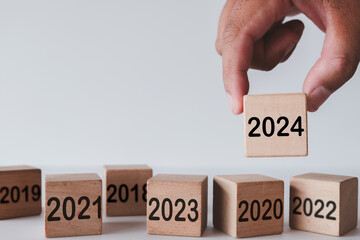 Happy New Year 2024,New goal,New plan,New Business concept.,Hand choosing wooden cube with 2024 text among 2019-2023 use for challenge,ew goals and achievements idea.