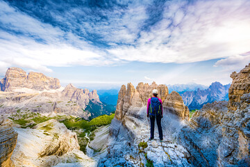 Young athletic woman enjoys summit view on Tre Cime from Paternkofel in the evening. Tre Cime,...