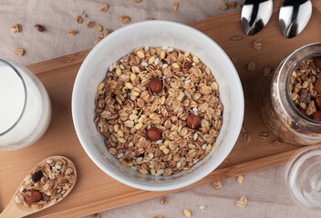 Muesli with nuts and milk on wooden board, top view
