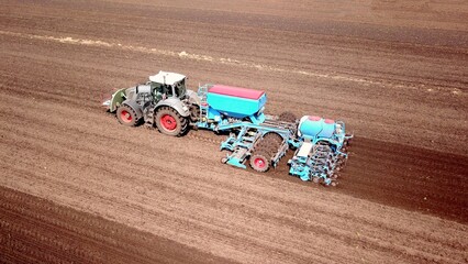 Tractor with a seed drill sowing on a field, aerial view, agriculture, birds-eye-view, aerial image