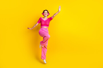 Fototapeta na wymiar Full size photo of good mood girl wear knit top pink pants having fun listening playlist dancing isolated on yellow color background