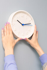 woman hangs a clock on the wall of the room.
