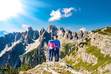 Athletic young couple enjoys epic view on Cadini di Misurina mountain range in the morning. Tre Cime, Dolomites, South Tirol, Italy, Europe.