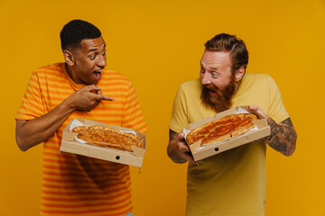 Two men screaming with thrill holding pizza while standing isolated