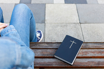 the bible lies on the bench next to the woman.