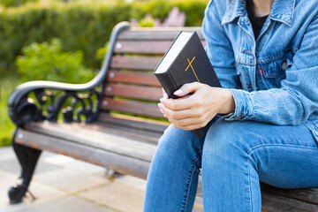 woman reading the bible sitting on a bench.