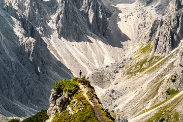 Athletic woman walks on super epic view point with Cadini group in the morning. Tre Cime, Dolomites, South Tirol, Italy, Europe.