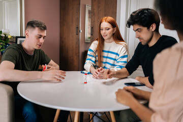 Best multiethnic friends having fun with charades cards play, enjoying board games activity for...