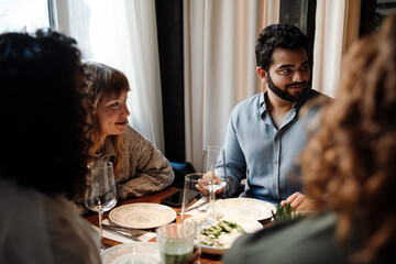 Group of smiling friends talking while dining in restaurant