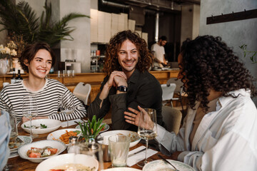 Group of cheerful friends talking while dining in restaurant