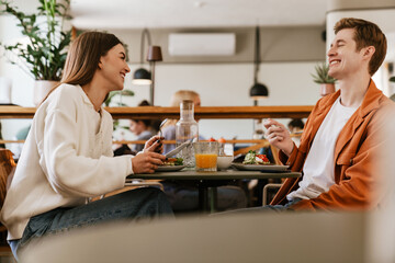 Cheerful couple having lunch together while sitting in cafe