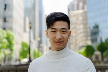 Closeup portrait of attractive handsome asian man looking at camera standing on city street