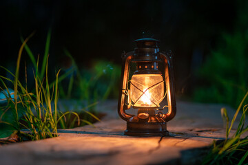 the antique oil lamp on the old wooden floor in the forest at night camping atmosphere