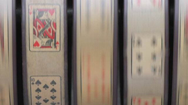 Close up of a weathered vintage slot machine with playing cards in action