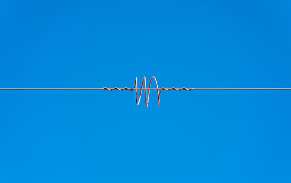 High voltage wires with a spiral coil against the blue sky. Twisted wire with white bondage. Industry. Electricity.