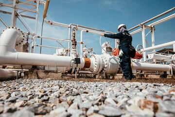 Production operator opening ball valve at pipeline oil and gas wellhead remote platform to control...