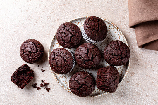 Top view of dark chocolate brownie muffins with beautiful structure. Homemade pastry. Beige background.