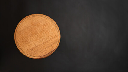 Round wooden plate on a dark background from above. Cutting board for cooking