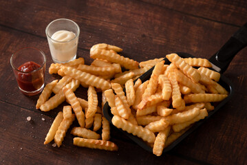 Closed up French fries on wooden table, serve with ketchup and mayonnaise sauce