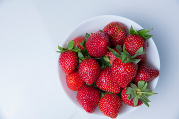 Fresh strawberries on a white plate, on a white background