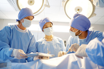 A team of doctors, surgeons are operating on a patient inside the emergency room.