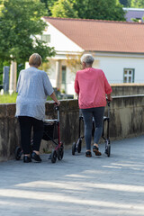 senior with rollator and crutch in springtime park