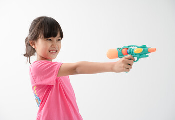 Happy Songkran Day, Asian kid girl hold water gun, Thai child funny hold toy water pistol and smile, isolated on white background, Thailand Songkran festival national culture concept