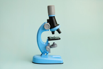 Children's toy microscope on a light blue background. An exact copy of a professional microscope with illumination for the stage during the study.