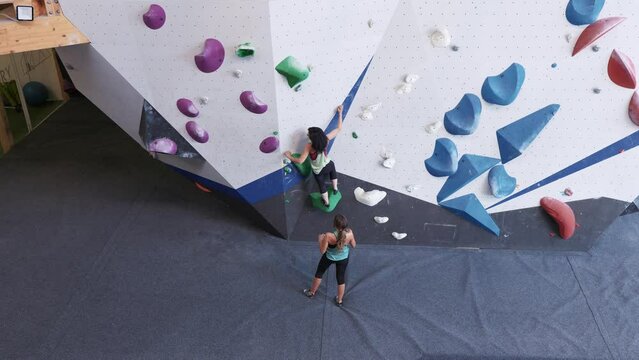 Women climbing bouldering wall with colorful grips