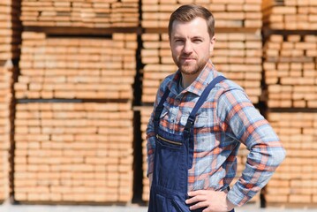 Fototapeta premium Joiner in uniform check boards on timber mill