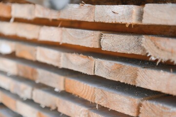 Stack of lumber of a wooden board from a tree, close-up, background. Wooden boards at the sawmill, carpentry workshop. Sawing and air drying of wood. Woodworking industry. Wooden boards