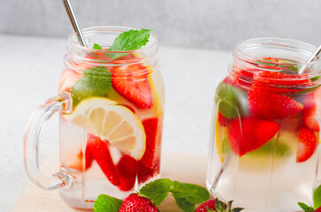 Strawberry Infused Water, Refreshing Cocktail, Lemonade, Detox Iced Drink with Fresh Strawberry, Lemon and Mint on Bright Background