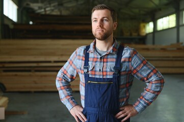Carpenter in the wood warehouse selects plank for furniture making in the carpentry workshop