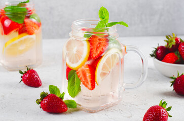 Strawberry Infused Water, Refreshing Cocktail, Lemonade, Detox Iced Drink with Fresh Strawberry, Lemon and Mint on Bright Background