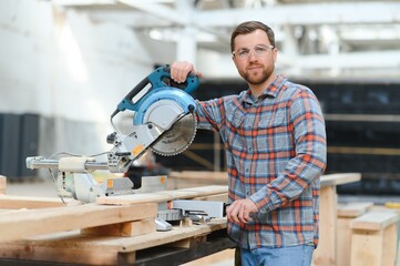 Wood cutting table with electric circular saw. Professional carpenter in uniform cutting wooden board at sawmill carpentry manufacturing . Sawing machine