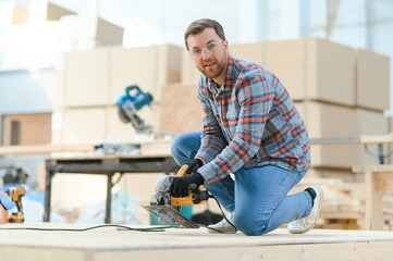 A carpenter works on woodworking the machine tool. Man collects furniture boxes. Saws furniture details with a circular saw. Process of sawing parts in parts. Against the background of the workshop.