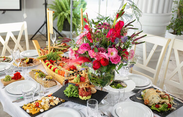 banquet table with a variety of dishes, flowers, and tableware