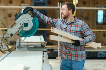 A carpenter works on woodworking the machine tool. Man collects furniture boxes. Saws furniture...