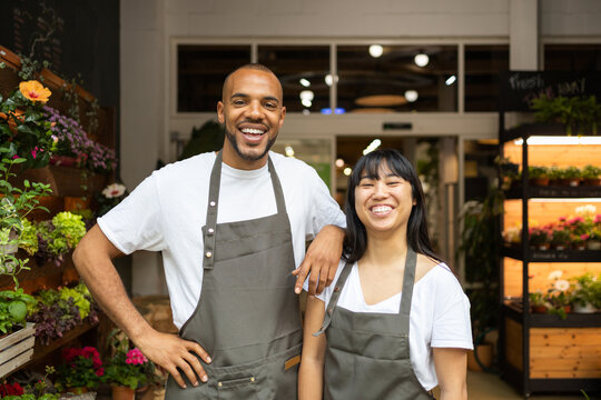 Happy multiethnic coworkers in aprons in floristry shop