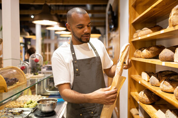 Serious black man putting bread in paper bag