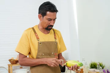 Fotobehang Close-up male chef holding a paring knife Use a knife to peel a large mango. Fast paring knife with knife skill when used frequently. This type of knife comes with the skills to use it safely. © Ekkasit A Siam