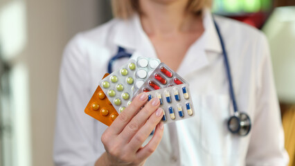 Female doctor holds different pills blisters in clinic