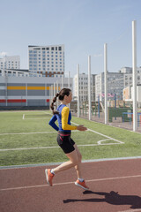 Fototapeta premium Running young woman in sportswear on stadium