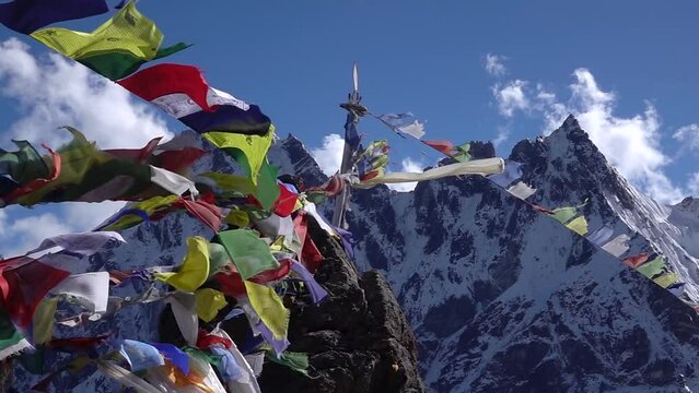 Tibetan colorful prayer flags flapping in the wind, himalaya 
at Renjo La pass with himalaya peaks in background and blue sky

