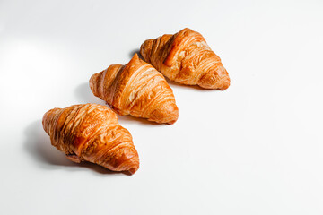 Three croissants on a white background, side view with space for text
